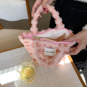 Detailed close-up of pink checkered fleece tote bag featuring a brand label and zipper