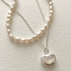 Macro view of sterling silver heart pendant with Baroque pearl and twisted chain details