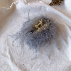 Top view of large gray ostrich feather hair claw clip on white fabric backdrop