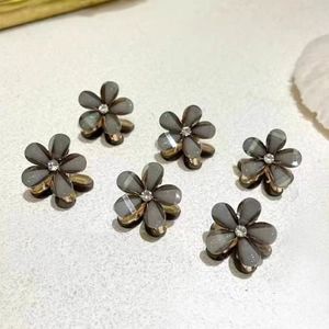 Detail of six mini flower hair clips with grey petals, rhinestones, and gold metal claws