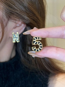 Detail of 18K gold plated asymmetric earrings with crystal letter N and number 5 charms