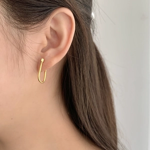 Close-up of a model wearing a polished gold U-shaped earring with minimalist square detail