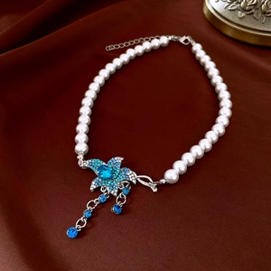 Macro shot of French vintage pearl necklace with a blue rhinestone flower pendant