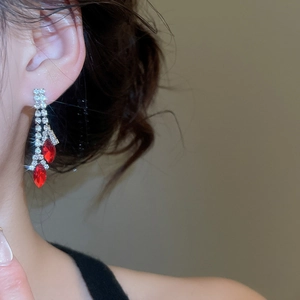Detail of long tassel earrings with sparkling rhinestones and a large red marquise gem