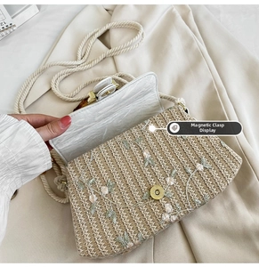 Detail shot of the magnetic snap closure on a straw woven bag with floral embroidery