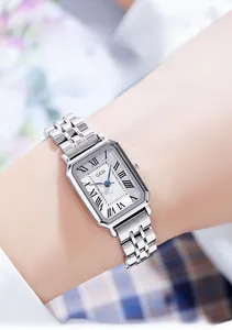 Close-up of elegant square silver watch with Roman numerals and blue hands on wrist