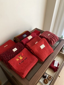 Detalle de varias bufandas rojas con texturas de punto, etiquetas de cachemira y flecos