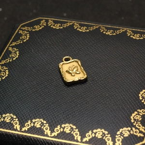 Detailed close-up of a golden butterfly pendant on a textured black jewelry box