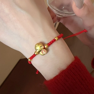 Détail d'un bracelet porte-bonheur rouge tissé main avec chat doré et caractère Ji