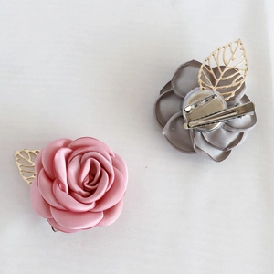 Boutonnière en rose rose et grise avec feuilles dorées et broche à double usage
