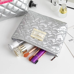 Détail de la trousse de maquillage argentée avec surpiqûres en cœur et zip