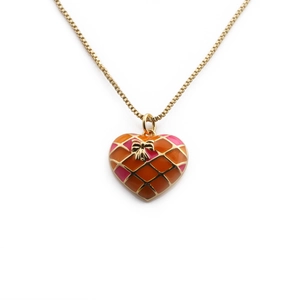 Gold-plated heart pendant necklace with orange pink enamel and bow detail on white background