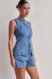 Vista laterale del set in denim con gilet sciancrato e pantaloncini, dettagli bottoni