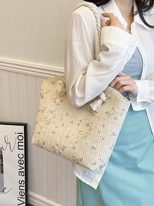 Sac fourre-tout en paille avec broderie florale et anses en corde porté par un mannequin