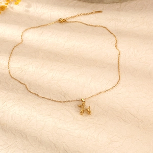 Elegant gold titanium steel necklace featuring a balloon dog pendant on beige background