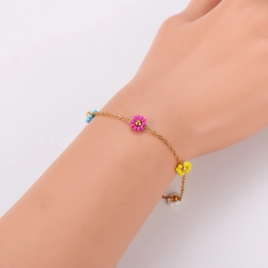 Floral charm bracelet with colorful beads on a gold chain worn by a female model