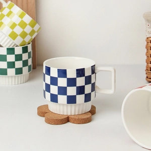 Detail of blue checkerboard ceramic mug with square handle on a cork flower coaster
