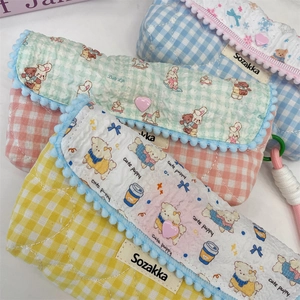 Close-up of quilted cotton pencil cases with pom-pom trim and cute animal patterns