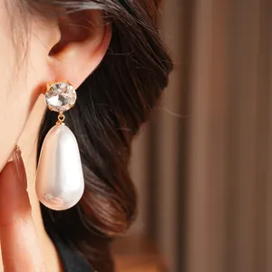 Elegant gold drop earrings featuring a sparkling zircon stud and large white teardrop pearl