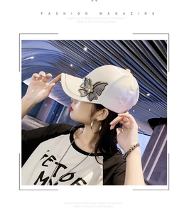 Detail of white satin baseball cap featuring mesh butterfly and rhinestone embellishment