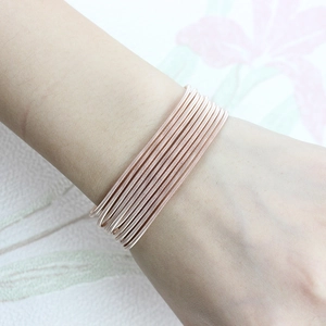 Detail of multi-layer rose gold coil bracelet with flexible spring design on wrist