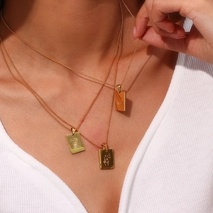 Close-up of gold layered pendant necklace with square charms and fine bead chains