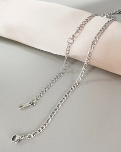 Macro shot of silver stainless steel Figaro chain necklace with lobster clasp detail