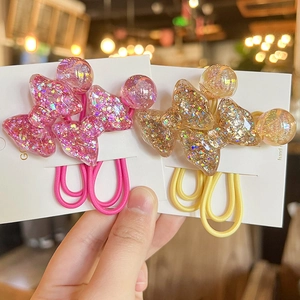 Close-up of glitter-filled resin bow hair ties in pink and gold with elastic bands