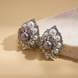 Vintage floral stud earrings with grey pearls and rhinestones on stone background