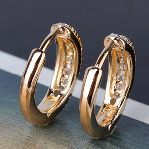 Macro shot of gold hoop earrings for men with inlaid clear zircon stones and textured finish