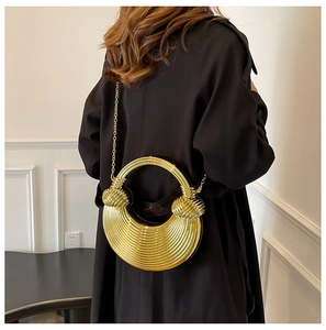 Sac pochette doré avec texture nervurée et détail de poignée à nœud sphérique sur modèle