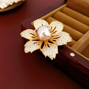 Macro shot of gold-plated flower brooch with champagne pearl and pavé cubic zirconia