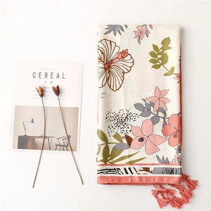 Detail of floral printed scarf with tropical hibiscus pattern and orange fringe tassels
