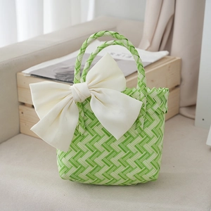Close-up of green and white woven basket bag with a large cream satin bow detail