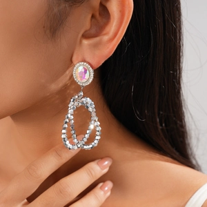 Close-up of model wearing silver geometric hollow earrings with sparkling rhinestones