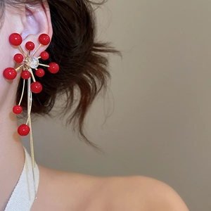Macro view of flower stud earrings with red beads and long golden fringe tassels
