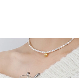 Close-up of elegant white pearl necklace featuring a golden spherical metal pendant