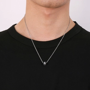 Détail de chaîne argentée avec un pendentif carré noir orné de la lettre A sur un mannequin