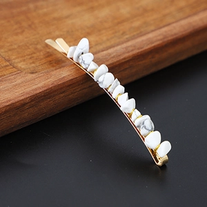 Detailed shot of golden hair pin with white marble natural stone beads on black surface