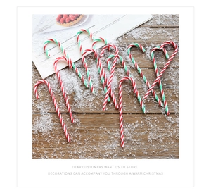 Detail of red and white striped Christmas candy cane ornaments on a snowy wood surface