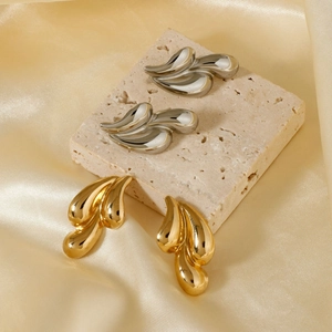 Elegant gold and silver teardrop stud earrings on stone tiles with silk background
