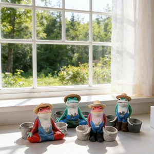 Set of four resin frog garden statues with straw hats and overalls on a sunlit windowsill