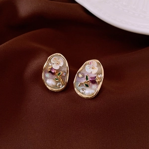 Dettaglio ravvicinato di orecchini vintage dorati con fiori in resina e perle eleganti