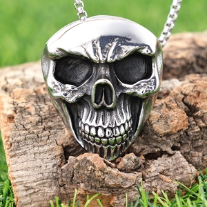 Polished stainless steel pirate skull pendant with chain on a natural bark background