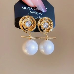 Macro shot of 14K gold plated swirl earrings with zircon petals and white pearls