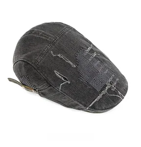 Détail de la casquette plate en denim gris foncé avec broderie croix rouge et effet usé