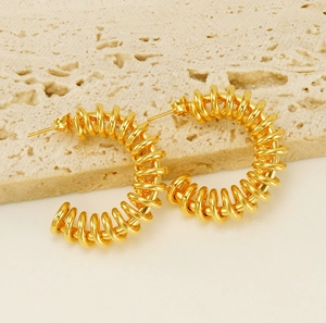 Detail of gold spiral C-shape hoop earrings with a polished finish and butterfly backs