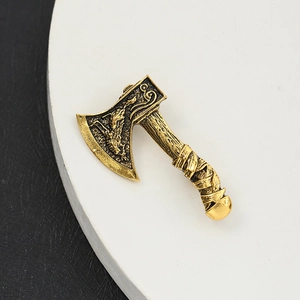 Golden axe brooch with intricate dragon engraving on a premium white circular stand