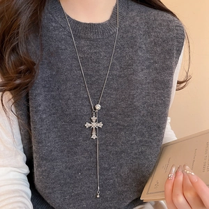 Vintage silver long cross necklace with metal beads styled on a grey sweater