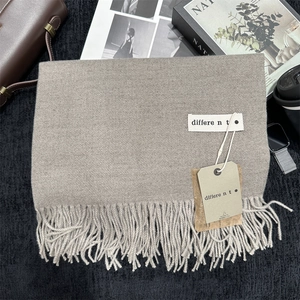 Close-up of khaki cashmere-feel scarf texture with soft fringe and stylish brand tag